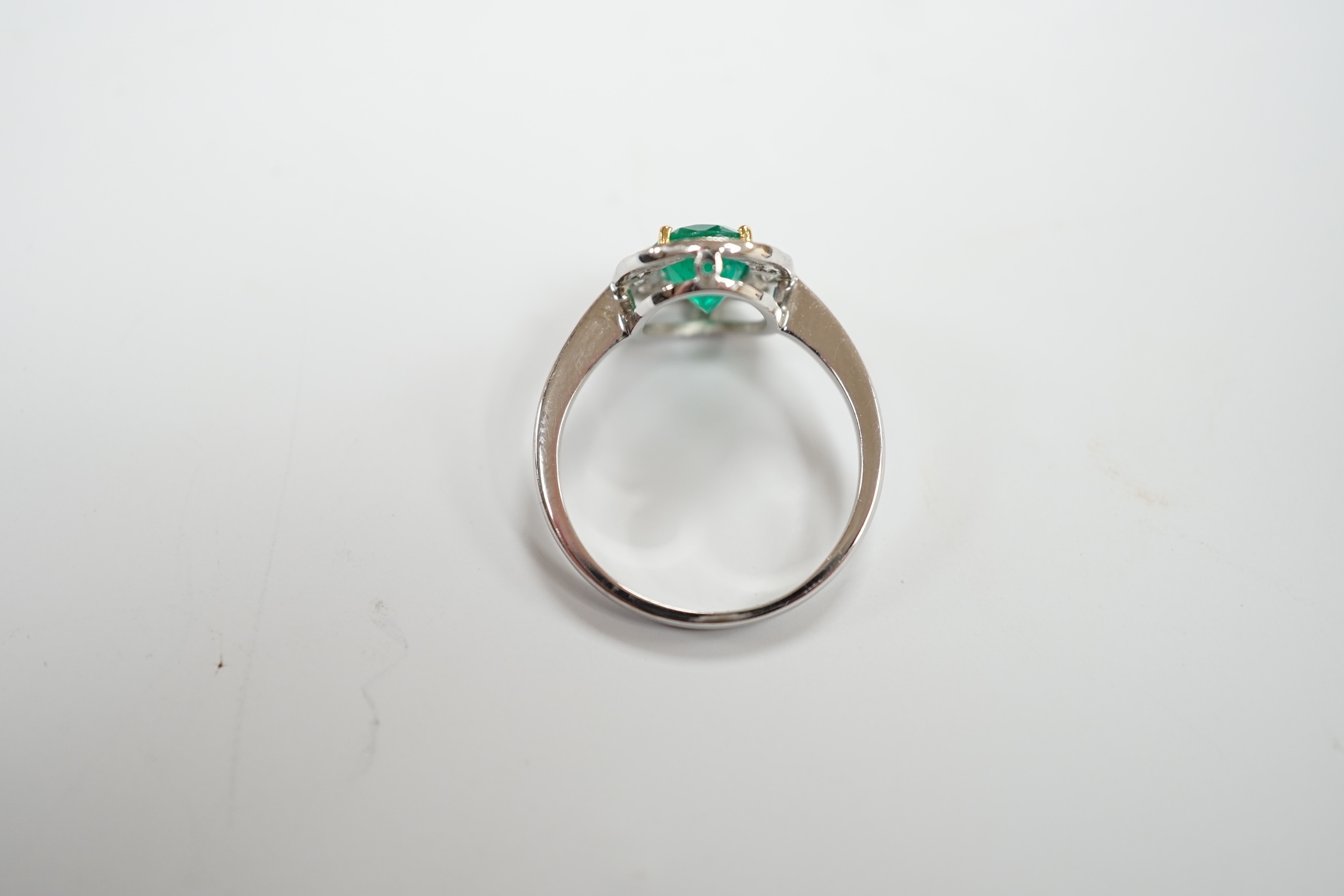 A white metal, emerald and diamond set oval cluster ring, size M, gross weight 2.8 grams.